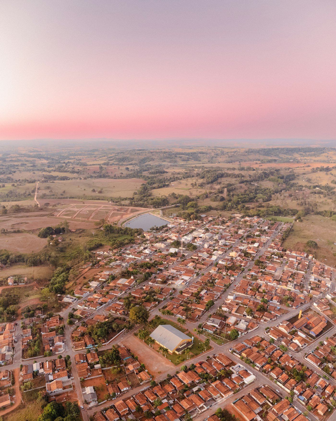 Vista aérea de região com loteamento residencial em desenvolvimento ao entardecer
